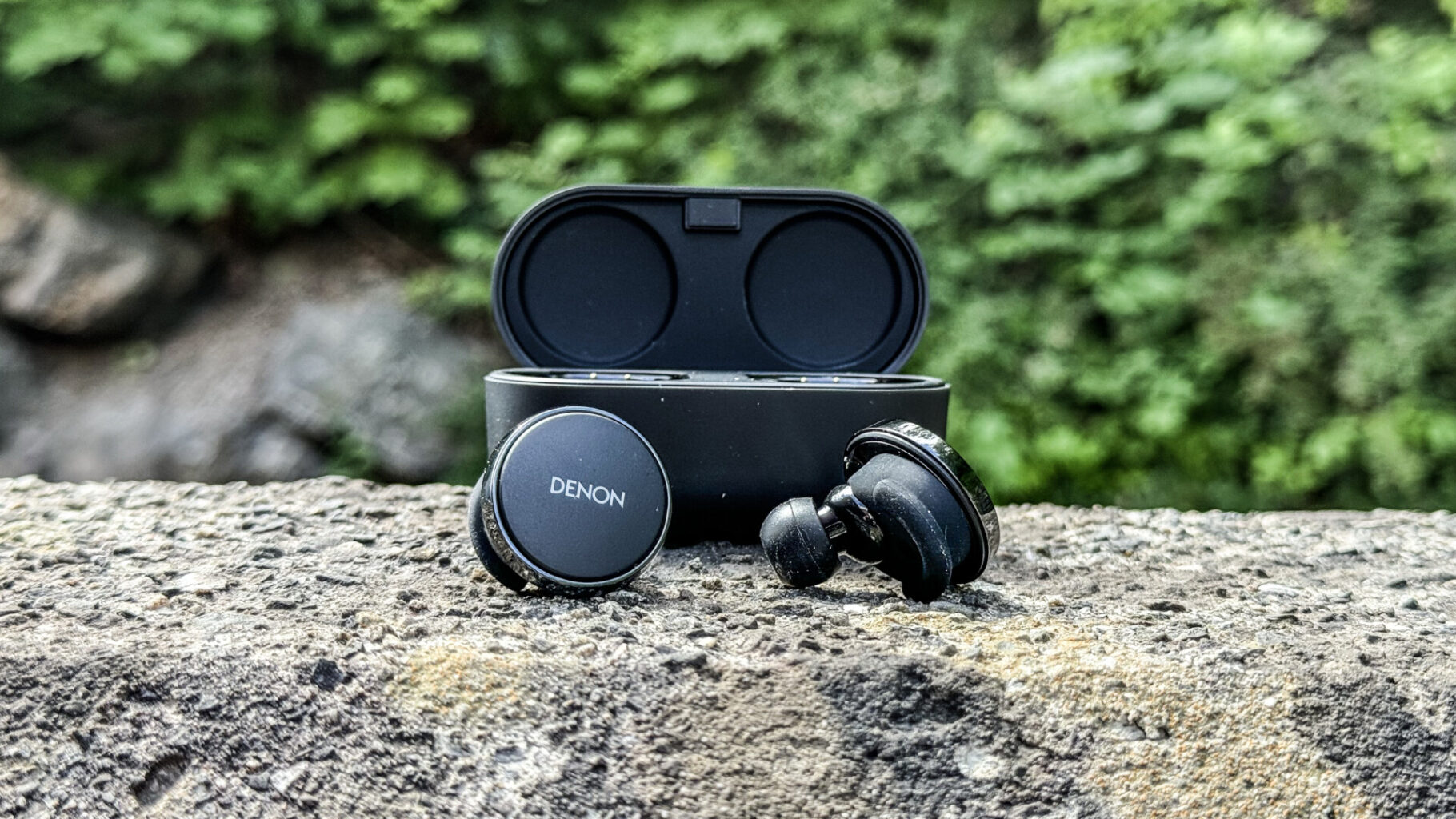 a black headphones and a case on a rock Denon PerL Pro - spread